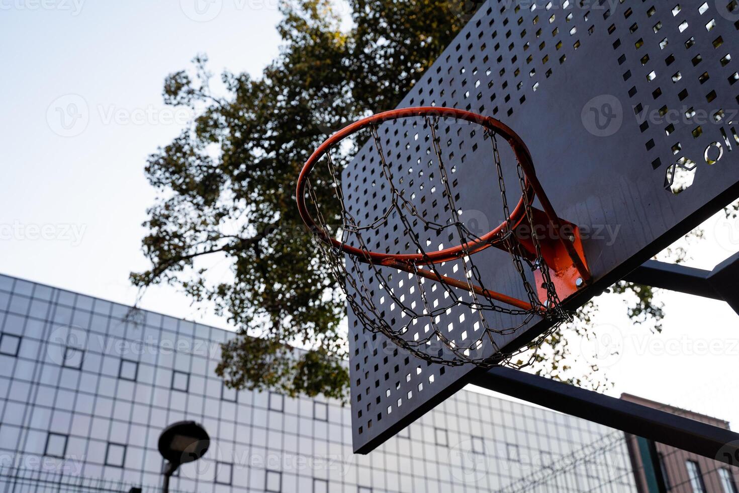 A vibrant urban basketball hoop stands out against the backdrop of modern architectural structures in the city photo