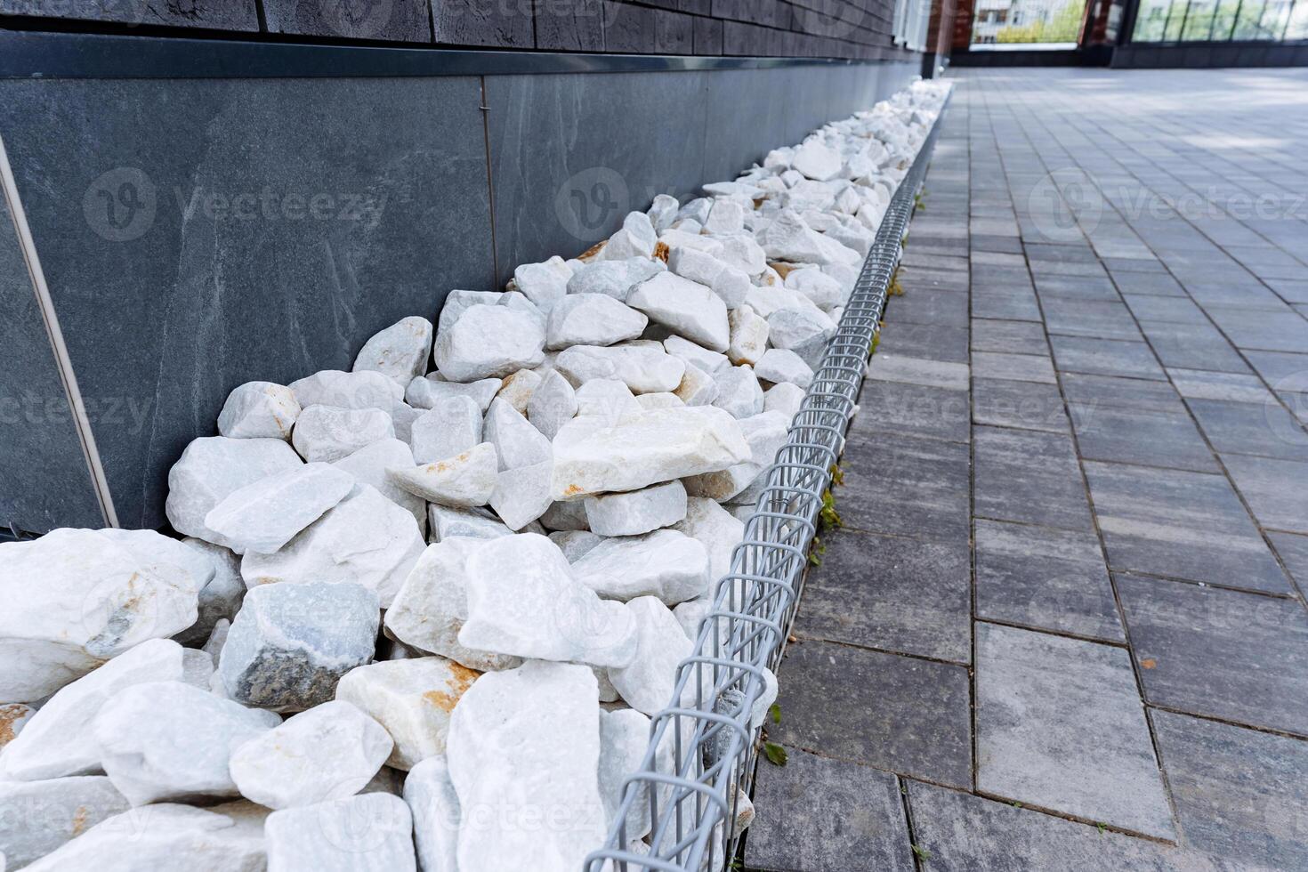 Beside the building, a decorative line of white rocks adorns the brick sidewalk, creating a visually appealing blend of textures and elements that enhance the areas aesthetic charm photo