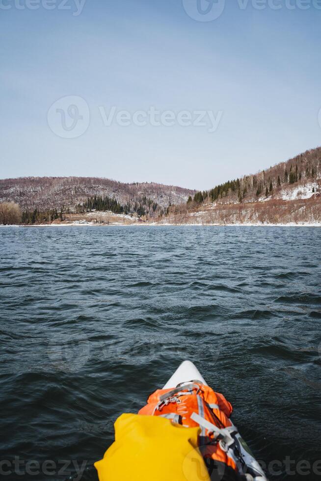 The bow of a boat against the background of the water surface, rafting on a mountain river on a SUP board, a beautiful spring landscape, melted waters. photo