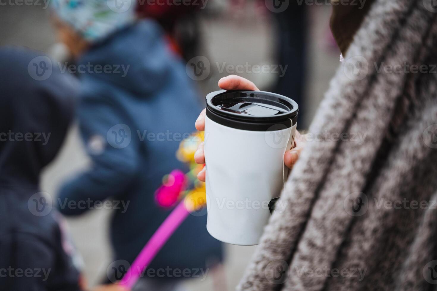 A woman is holding a cup of steaming coffee in her hand as she enjoys the rich aroma and warmth it provides, savoring every moment of her simple yet delightful drink experience photo