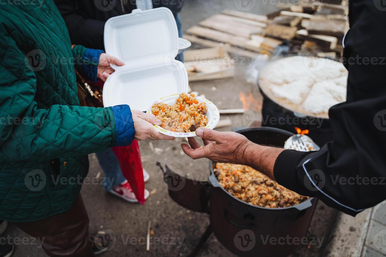 A person is giving a plate of food to another person photo