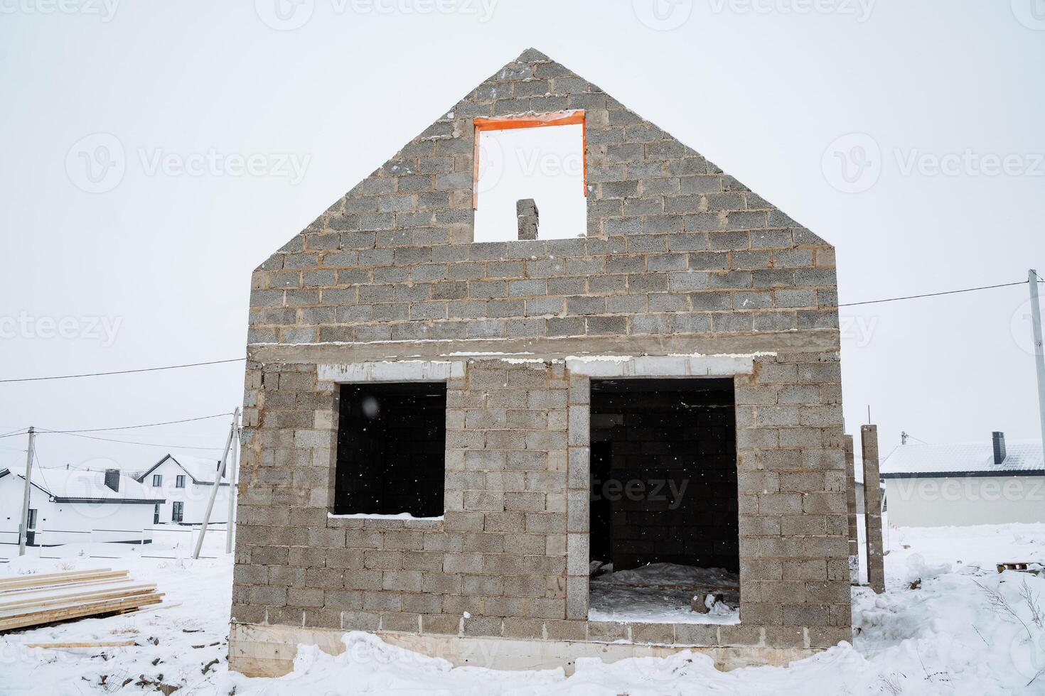 A sturdy brick house is currently under construction amidst thick, beautiful white snow, which emphasizes the unique challenges and aesthetic value of building in harsh winter conditions photo