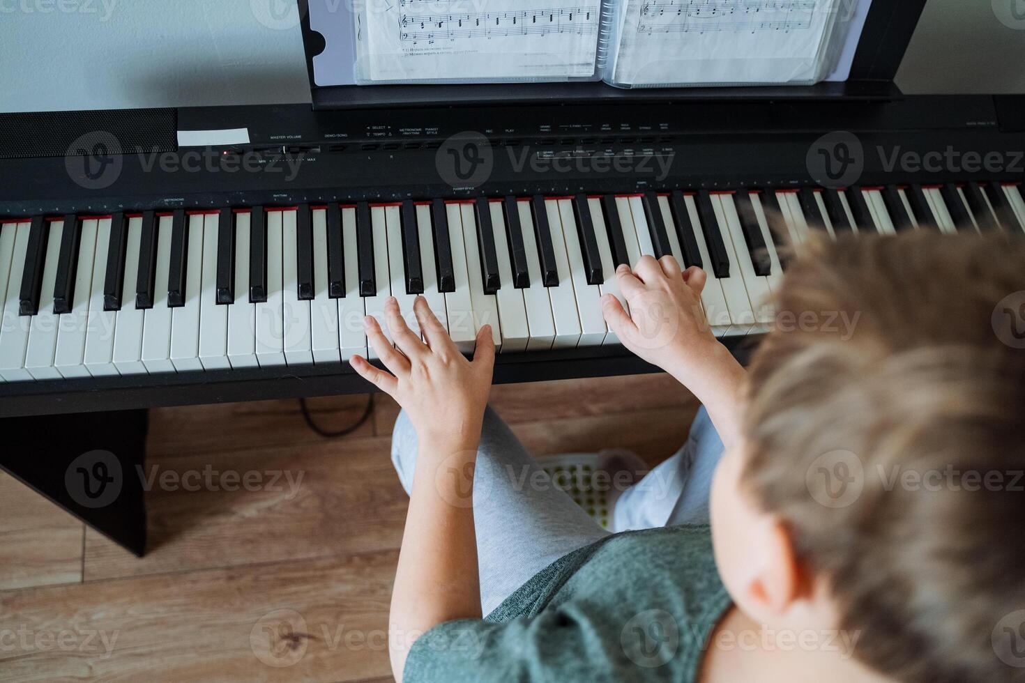 A young boy is happily playing a piano in a cozy living room, showcasing his musical talent and joy as he interacts with the instrument and enjoys creating beautiful melodies photo