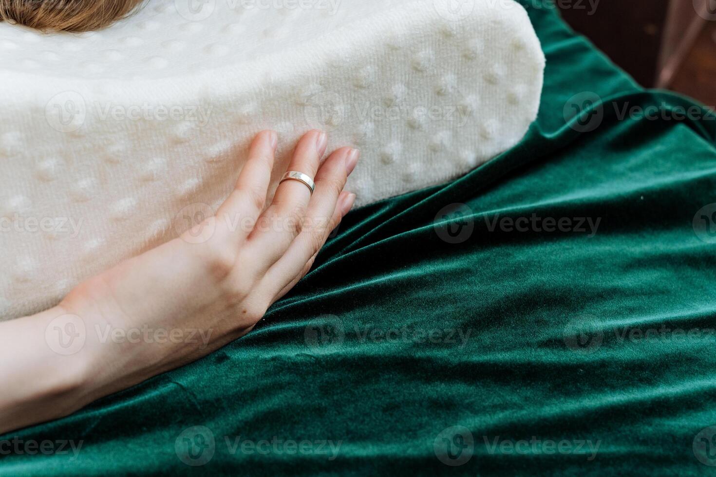A beautifully captured moment shows a hand pressing a plush white foam pillow against a luxurious green velvet backdrop, emphasizing textures and intricate design details photo