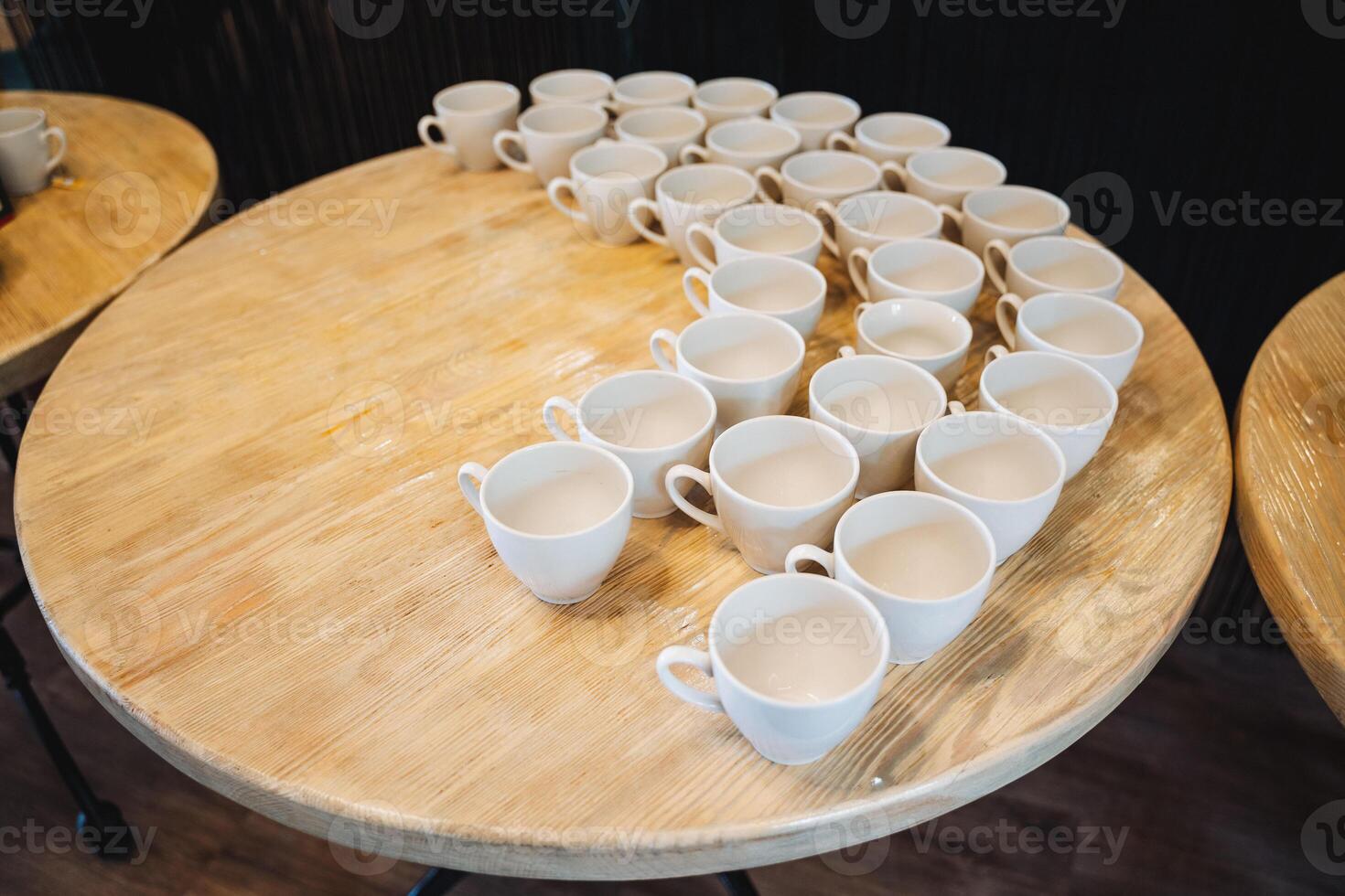 A beautifully crafted wooden table that features an assortment of empty coffee cups arranged neatly in rows, showcasing a minimalist yet inviting aesthetic for any setting photo