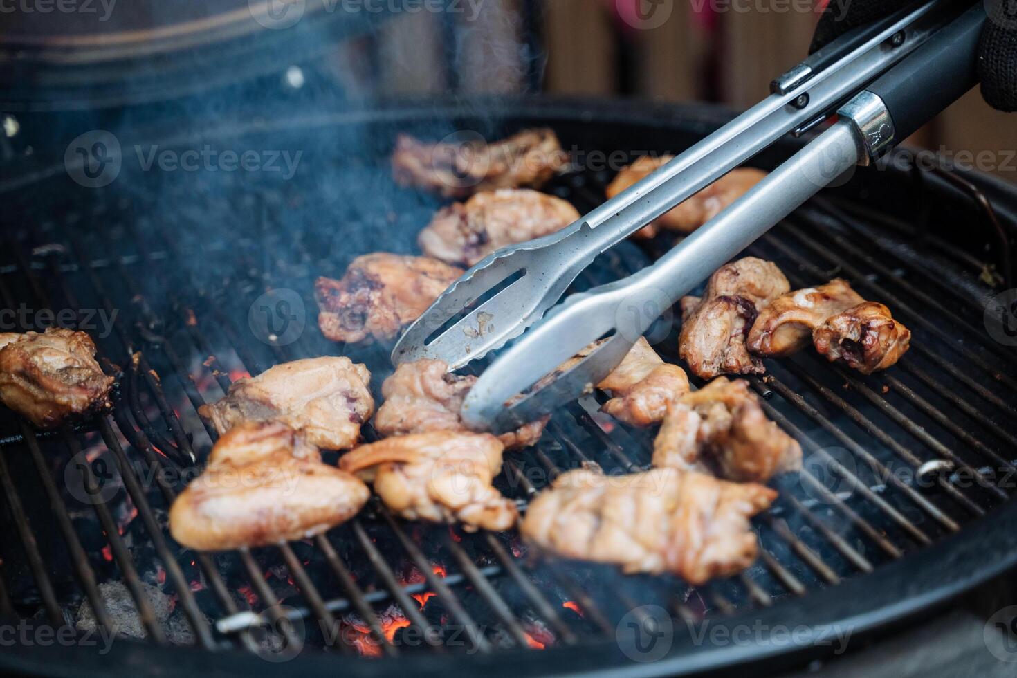 Chicken wings sizzle on the grill, expertly flipped for even cooking. Outdoor grilling enhances flavor, creating a mouthwatering dish. Enjoy the process and delicious result photo