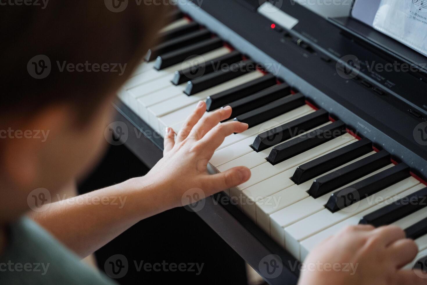 A person is skillfully playing a piano, with their hands actively dancing across the keys, producing beautiful music as they express themselves through this wonderful instrument photo