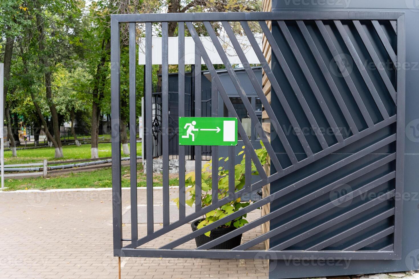 There is a metal gate that features a green exit sign clearly visible on it photo