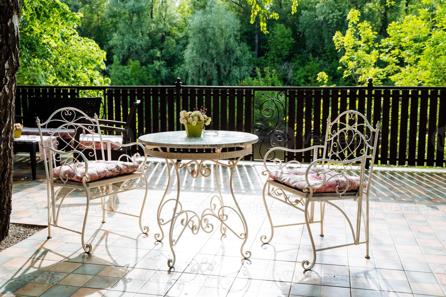 A table and chairs on a patio with trees in the background photo