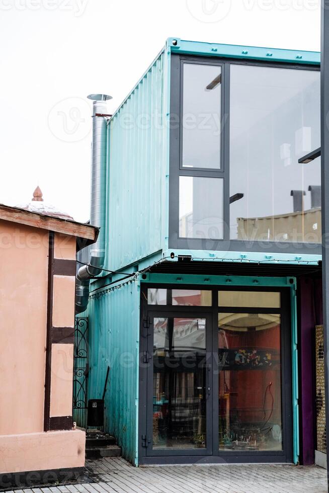 A modern building constructed using shipping containers features numerous windows that allow plenty of natural light to enter, enhancing the overall aesthetic appeal and functionality photo
