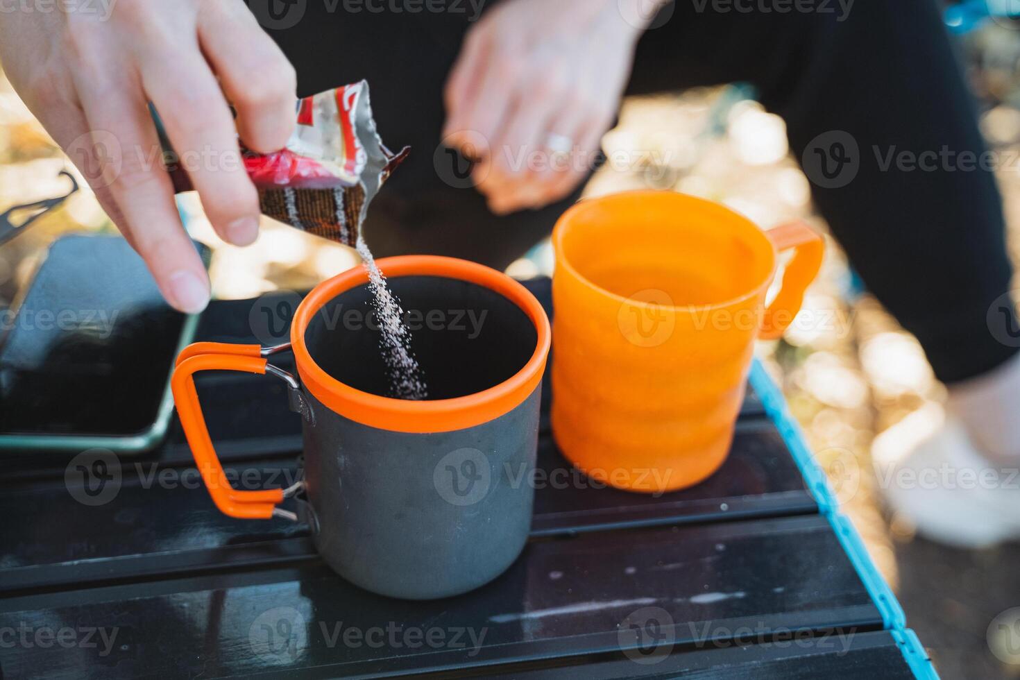 A person is skillfully and carefully pouring water into a cup that is placed on an ordinary table, demonstrating a simple yet essential action that many individuals engage in daily life photo