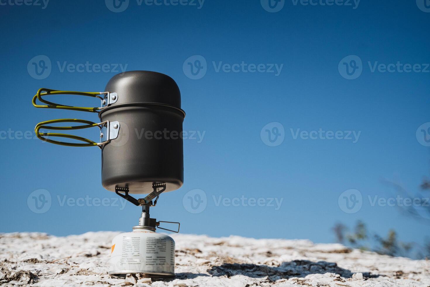 A pot is currently sitting on top of a propane burner on a snowy hill photo