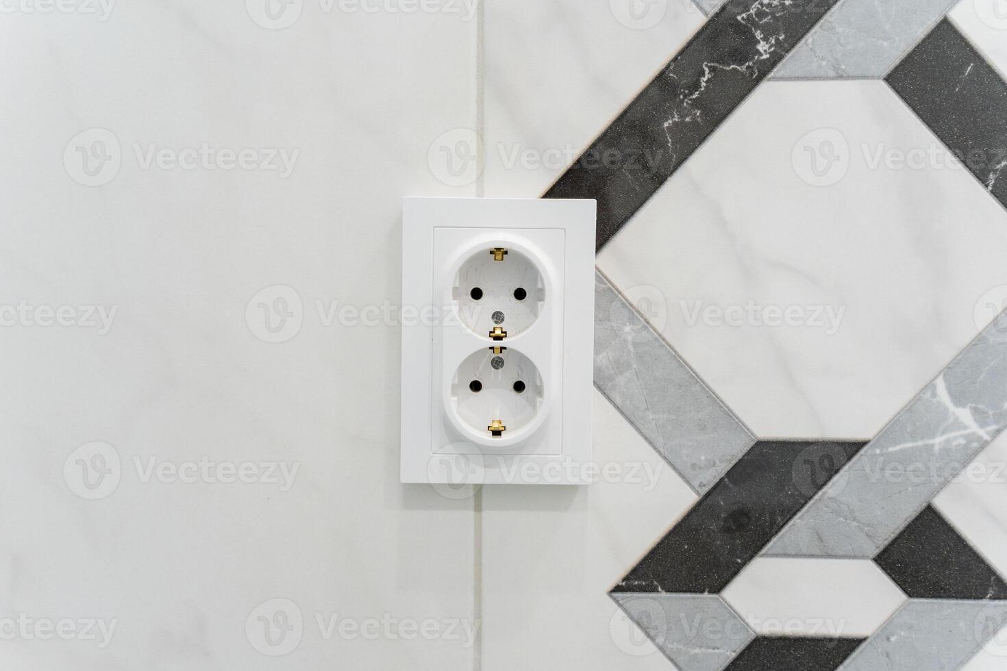 This image shows a closeup of a white electrical outlet on a tiled wall, emphasizing its thoughtful design, placement, and functionality, blending aesthetics with practicality photo
