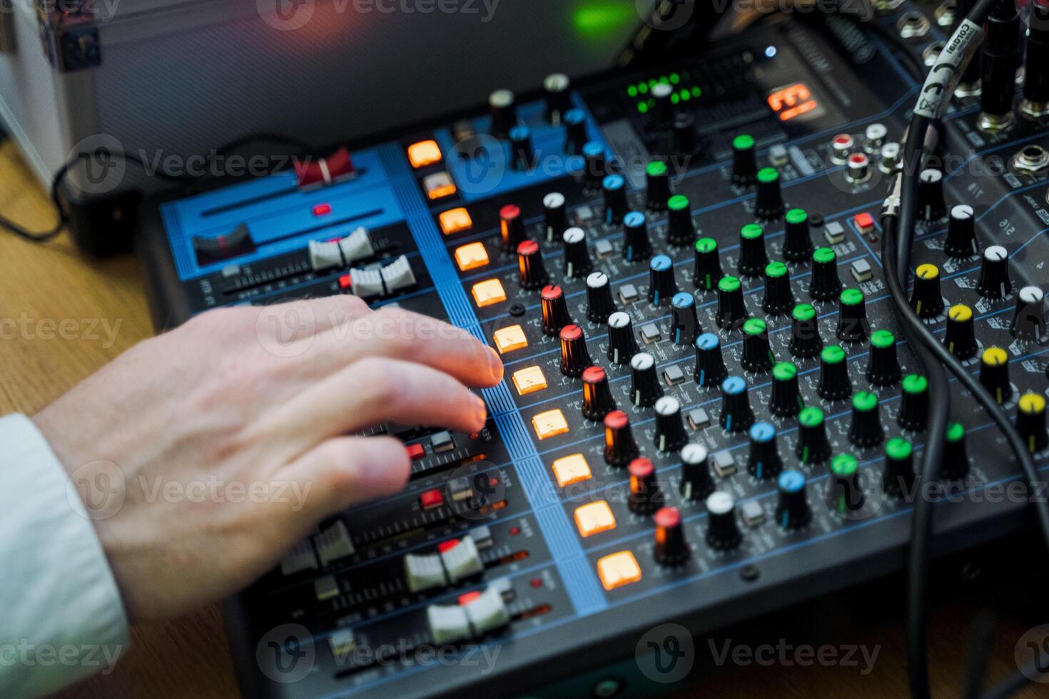 Sound engineer manipulating knobs on mixing console for audio mixing at event photo