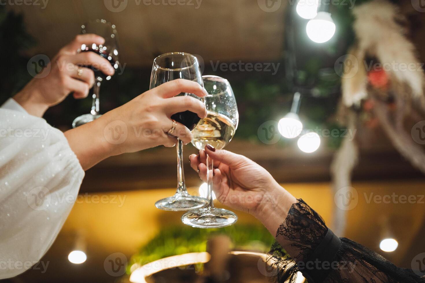 At a lively party, two individuals enthusiastically raise their wine glasses to toast each other, celebrating good times and camaraderie. Their gestures signify joy and connection photo