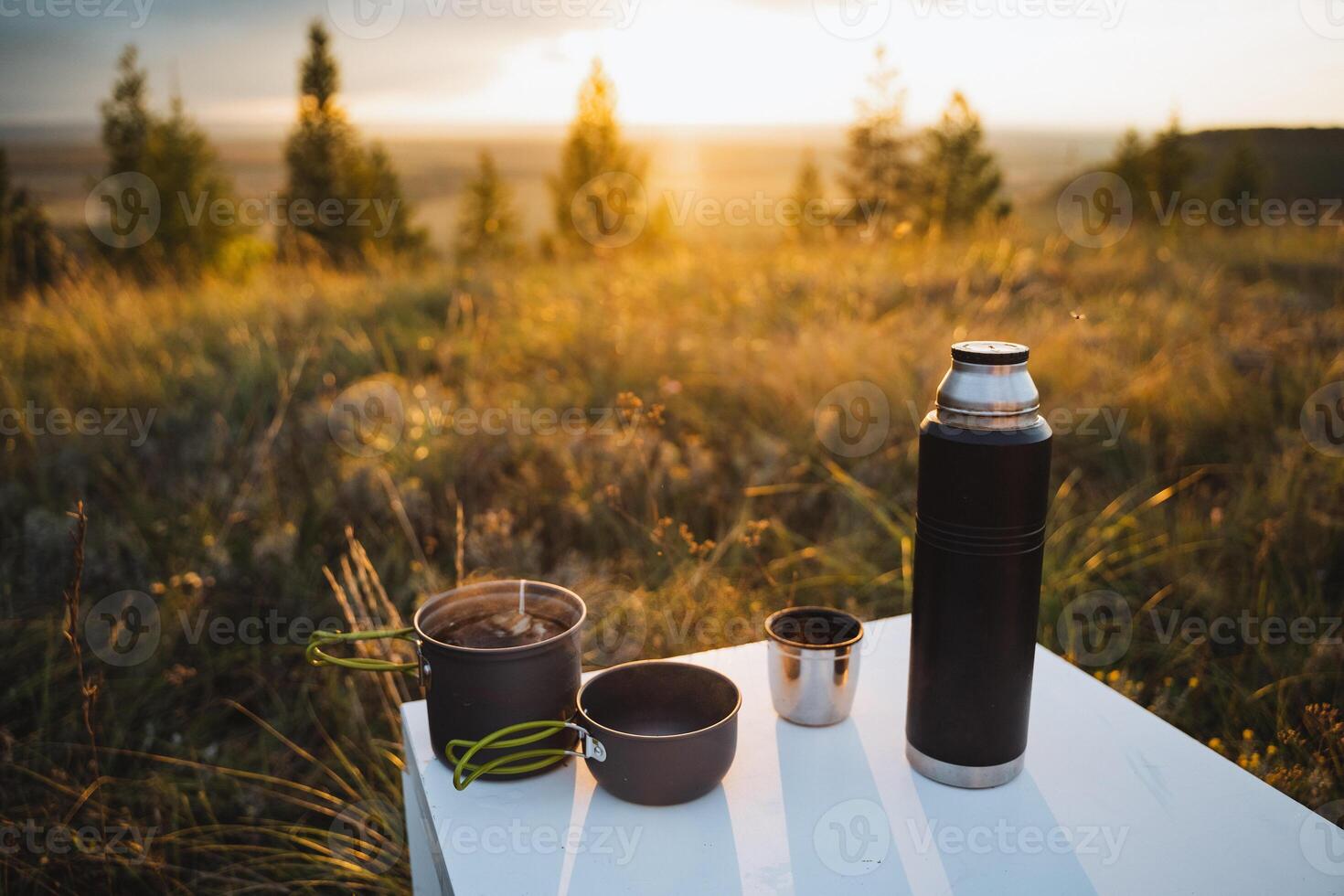 Enjoy a picturesque outdoor picnic setup complete with a thermos and essential cooking utensils, all amidst the loving embrace of nature photo