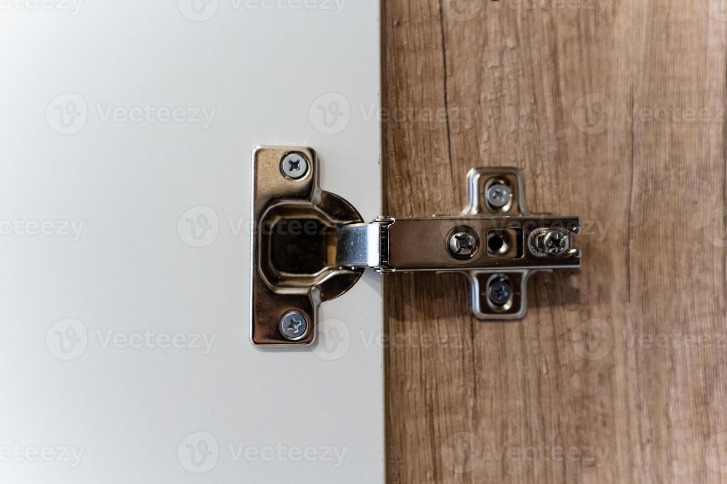 This closeup image vividly displays a modern cabinet hinge that is securely attached to a stylish wooden door design photo