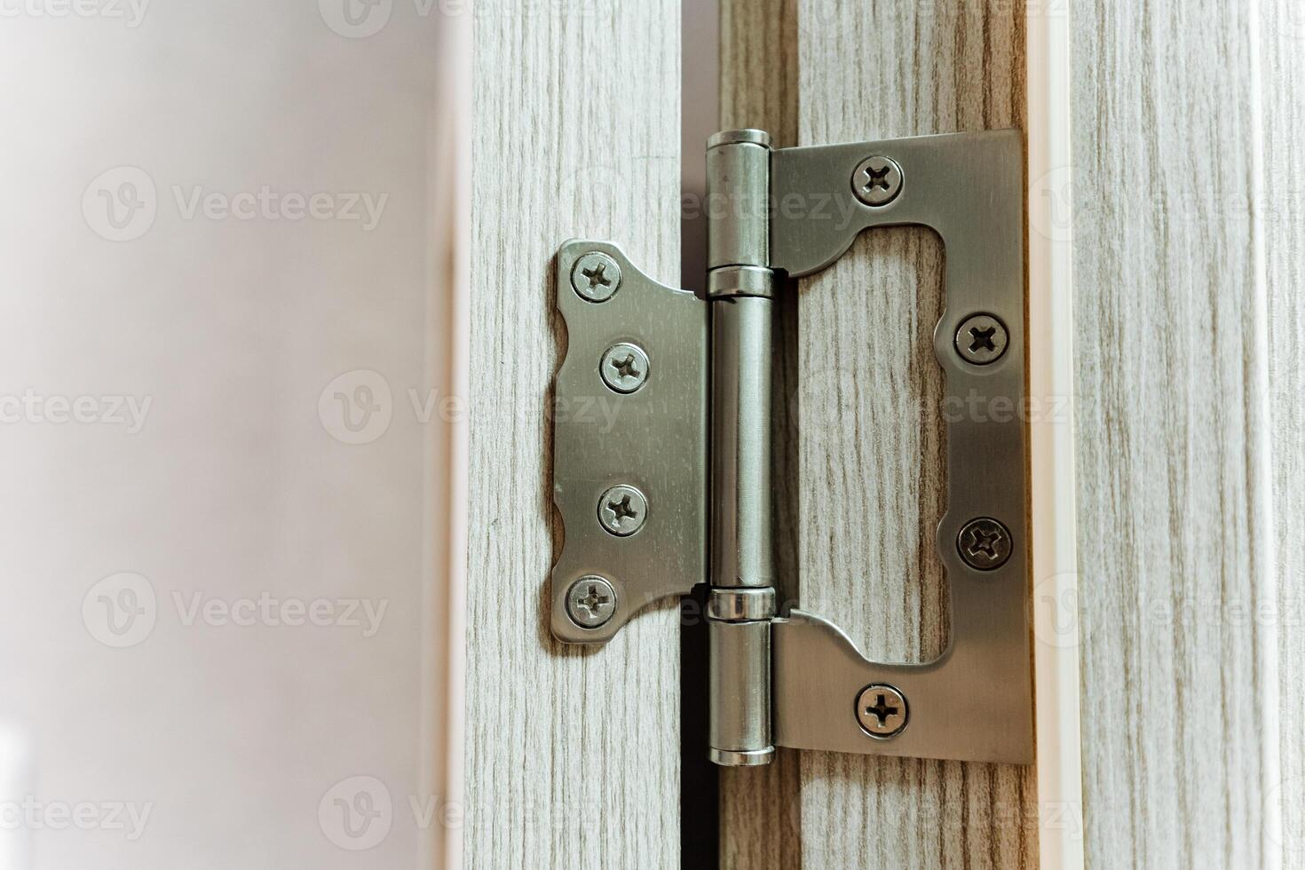 This detailed closeup photograph prominently showcases a door hinge that can be found on a beautifully crafted wooden door, emphasizing both its elegant design and practical functionality photo