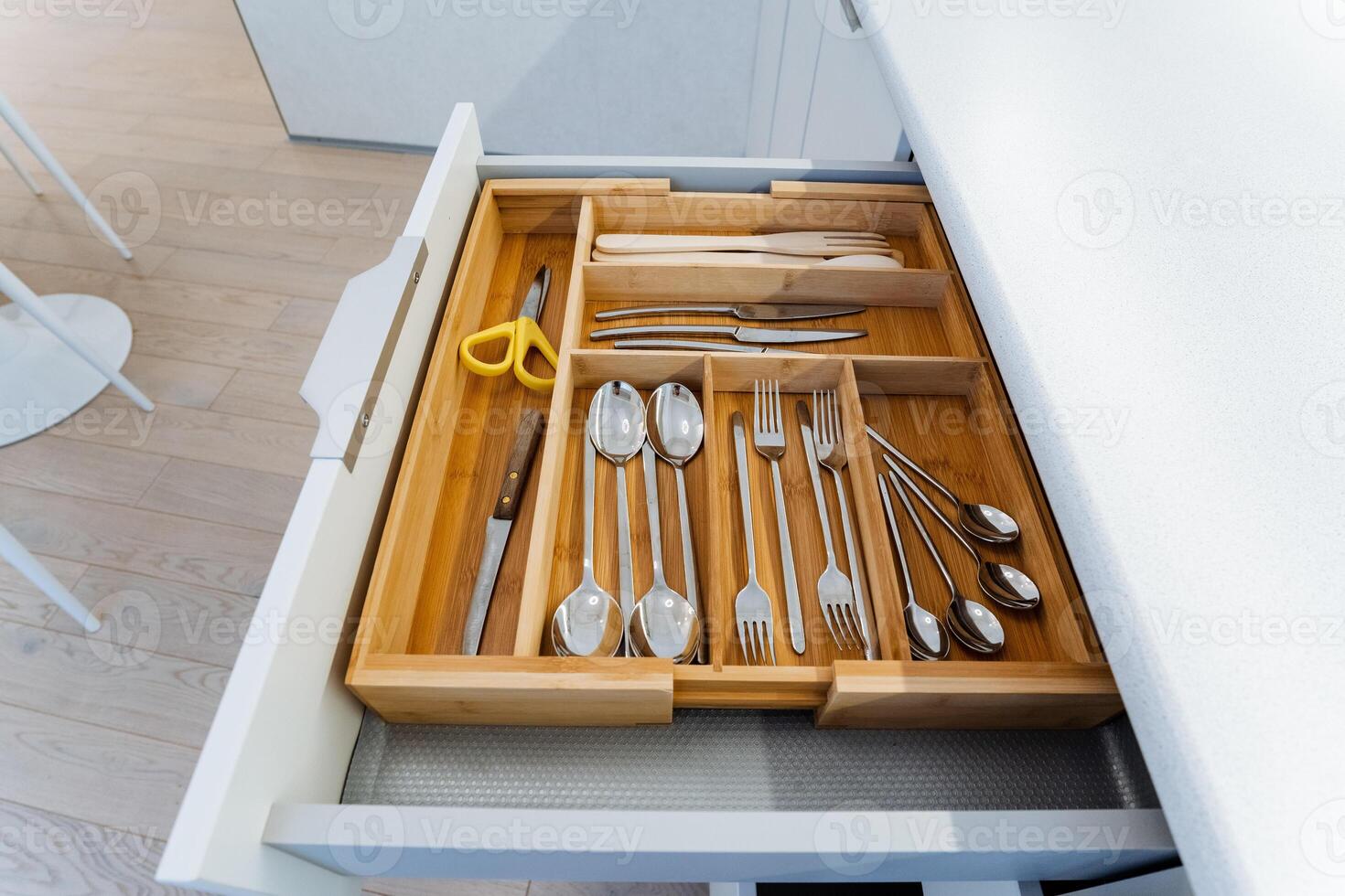 The wooden drawer in the kitchen displays silverware and scissors, highlighting the craftsmanship with hardwood and metal. The mix of materials enhances the kitchens charm photo