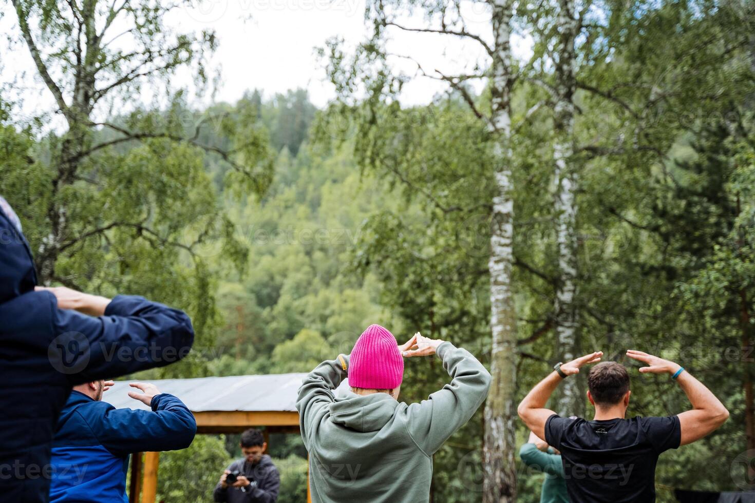 A group of individuals exercising in a scenic forest, fostering bonds, prioritizing fitness, and appreciating nature. Its a joyful and green experience of community and wellness photo