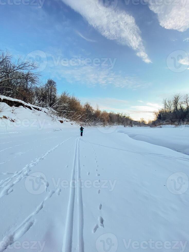 A person is leisurely walking down a snow covered road, enjoying the serene beauty of winter and the glistening white landscape all around them, taking in the crisp, cold air photo