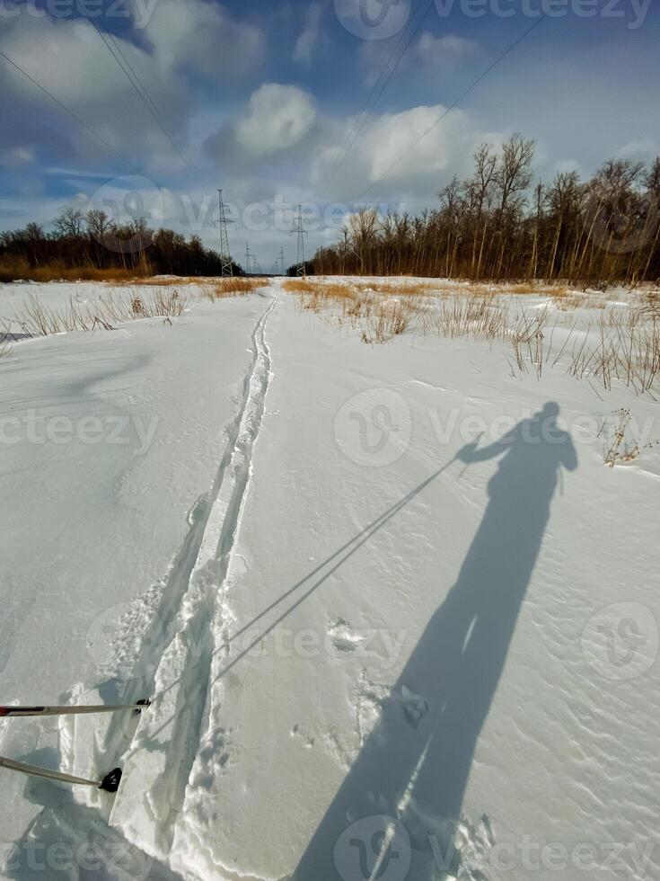 A shadow of an individual is prominently cast on a snowy road, highlighting the winter conditions and the beauty of the glacial landscape surrounding it, creating a picturesque scene photo
