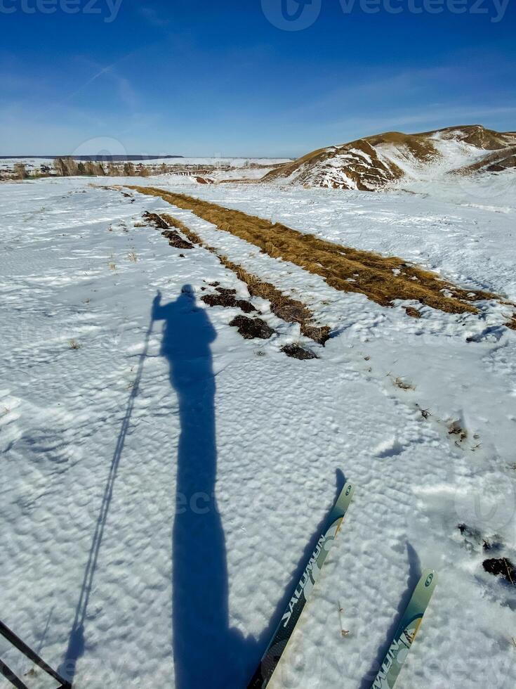 On a beautiful winter day, a clear silhouette of a person gracefully skiing down a pristine slope, skillfully creating intricate patterns in the untouched, glistening snow below them photo