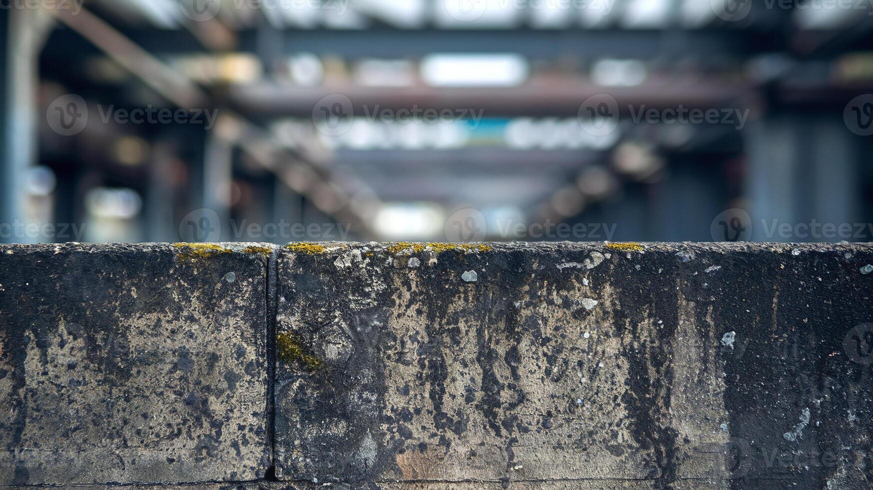 Weathered Concrete Wall with Industrial Steel Beams in Blurred Background Reflecting Urban Decay photo