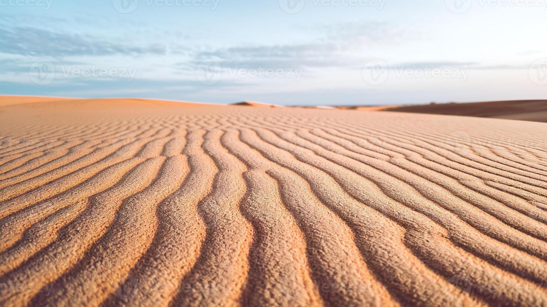 Golden Sand Dunes with Rippling Patterns Under Soft Light and Blue Sky Horizon in a Tranquil Desert photo