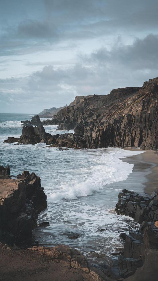 Rugged Coastal Cliffs with Crashing Ocean Waves and Moody Sky in a Remote Natural Setting photo