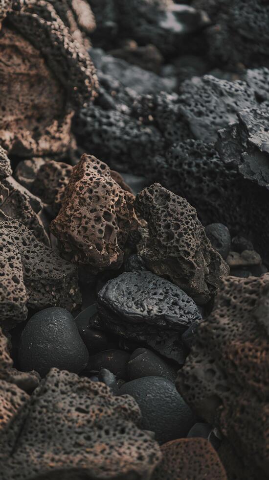 Closeup of Natural Volcanic Rocks with Textured Surfaces on Dark Rocky Shoreline in Soft Lighting photo