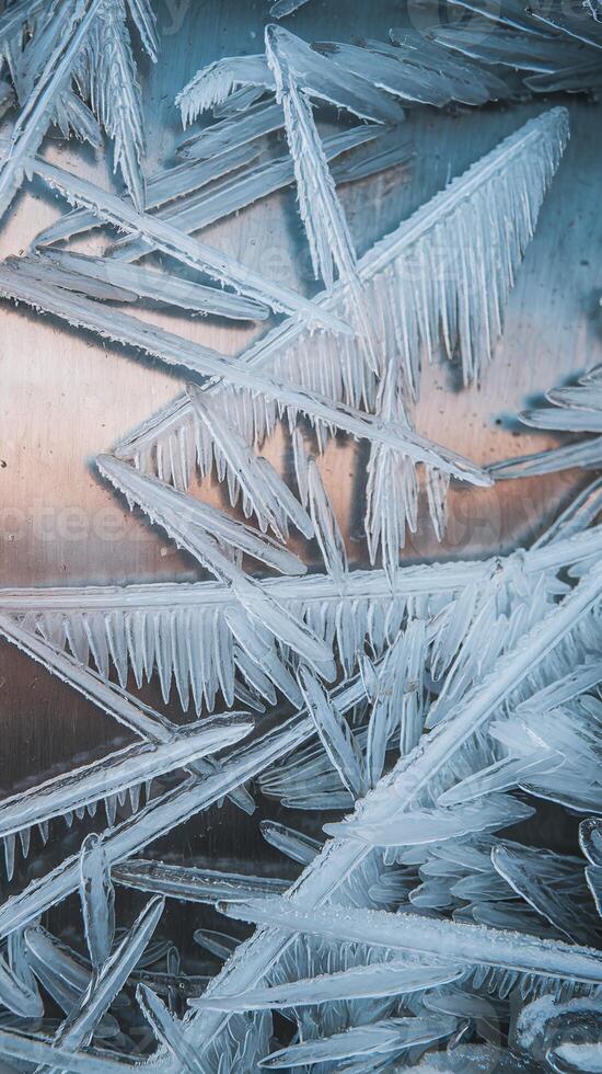 Closeup of sharp triangular ice crystals with natural patterns on smooth metallic background in winter photo