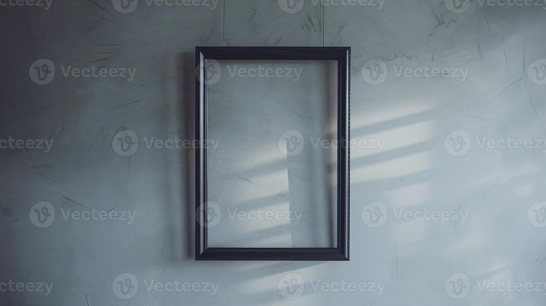 Empty Black Frame on Gray Concrete Wall with Natural Light and Shadow Patterns photo