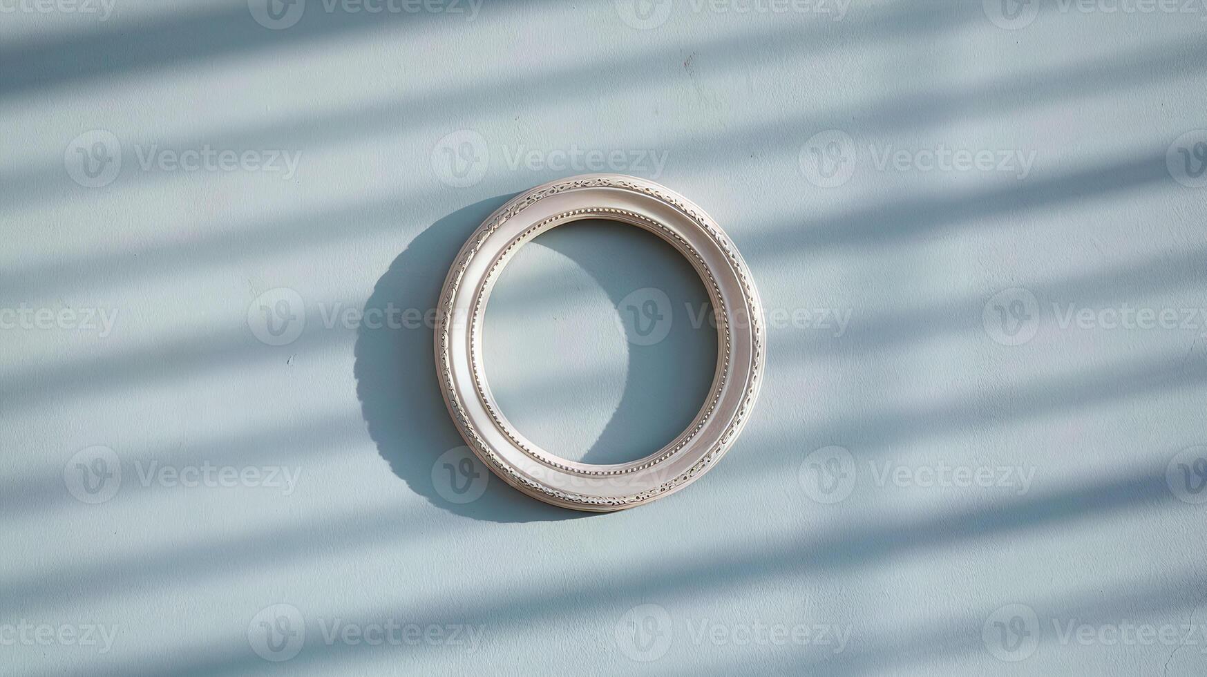 Minimalist White Circular Picture Frame Hanging on Light Blue Wall with Shadow Patterns from Window Blinds photo
