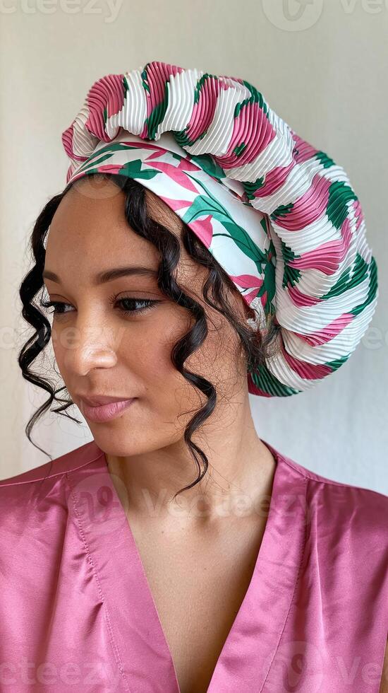 Woman Wearing Pink and White Satin Bonnet with Green Leaf Pattern and Curly Hair Against White Background photo
