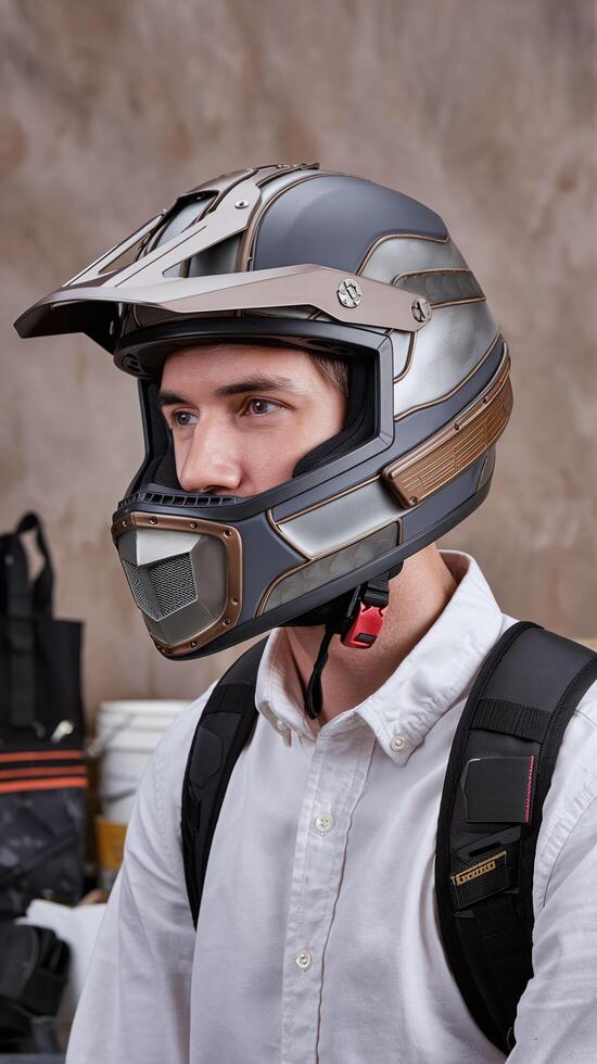 Man Wearing Futuristic Matte Gray Helmet with Metallic Details Indoors Against Neutral Background photo