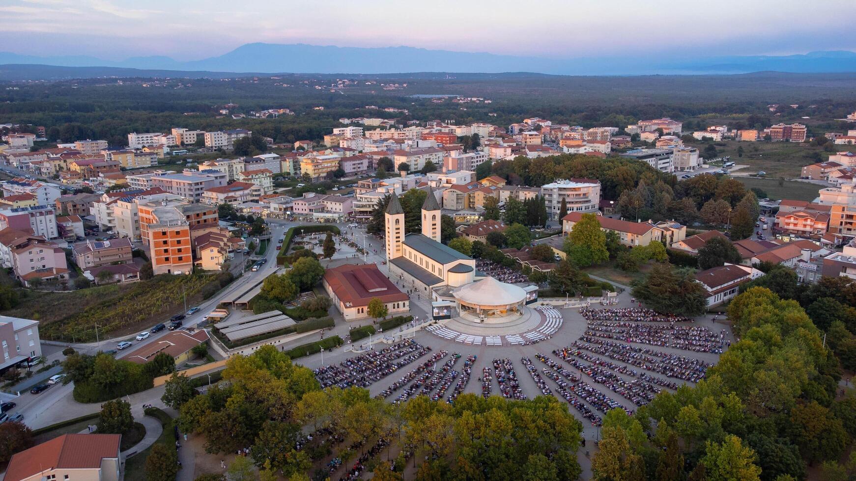 Sunset over medjugorje. Aerial view of the church and a gathering of people attending a religious celebration. photo