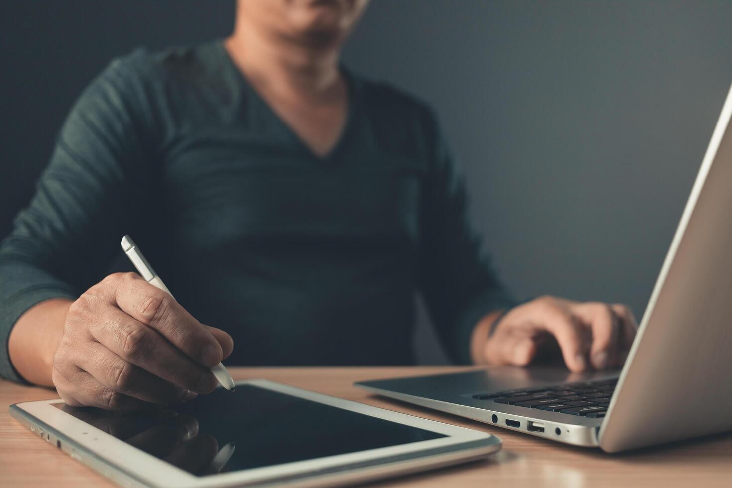 Man working using a notebook computer and using a tablet ,sits on the chair in the living room at home office. photo