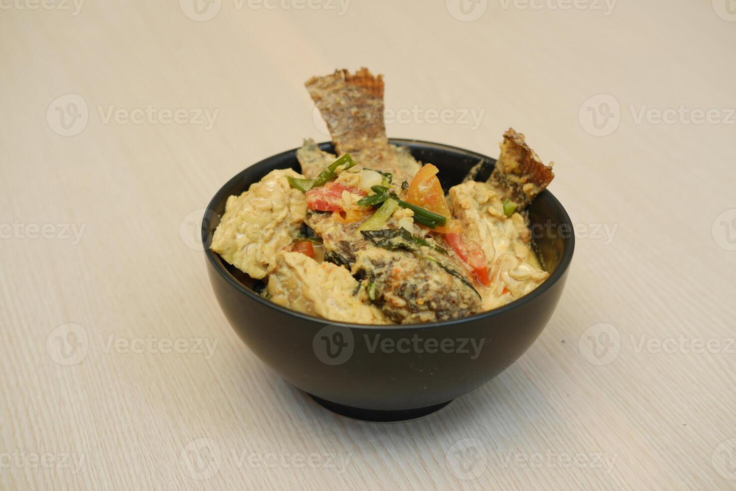 Fried fish with curry in a bowl on a wooden table. photo