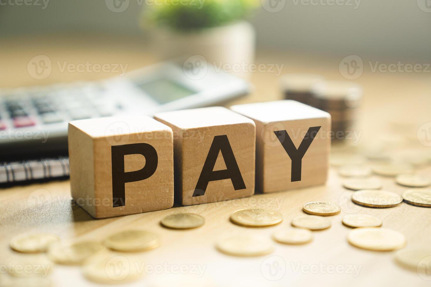 Wooden blocks spelling PAY placed on a desk with coins, calculator, and notebook, symbolizing salary payment, financial transaction, payroll, budgeting, and business expense management photo