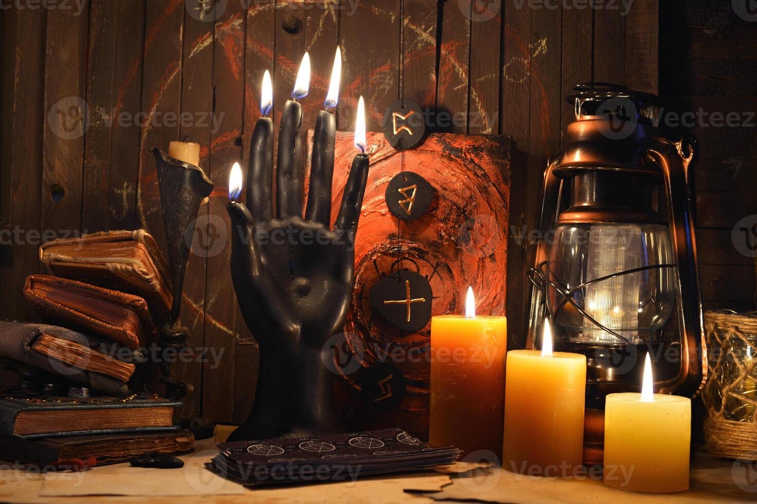Black candle as scary hand, magic spell book, old lamp, runes and witchy ritual objects on altar table. Occult, esoteric, wicca, Halloween and gothic concept. photo