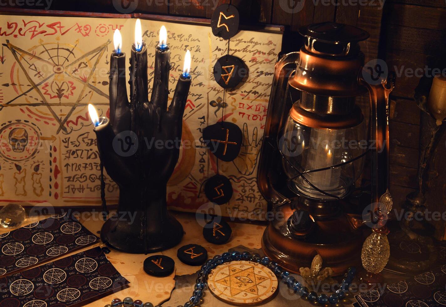 Mystic still life with tarot cards, runes and black candle as scary hand on witch table. Halloween concept photo