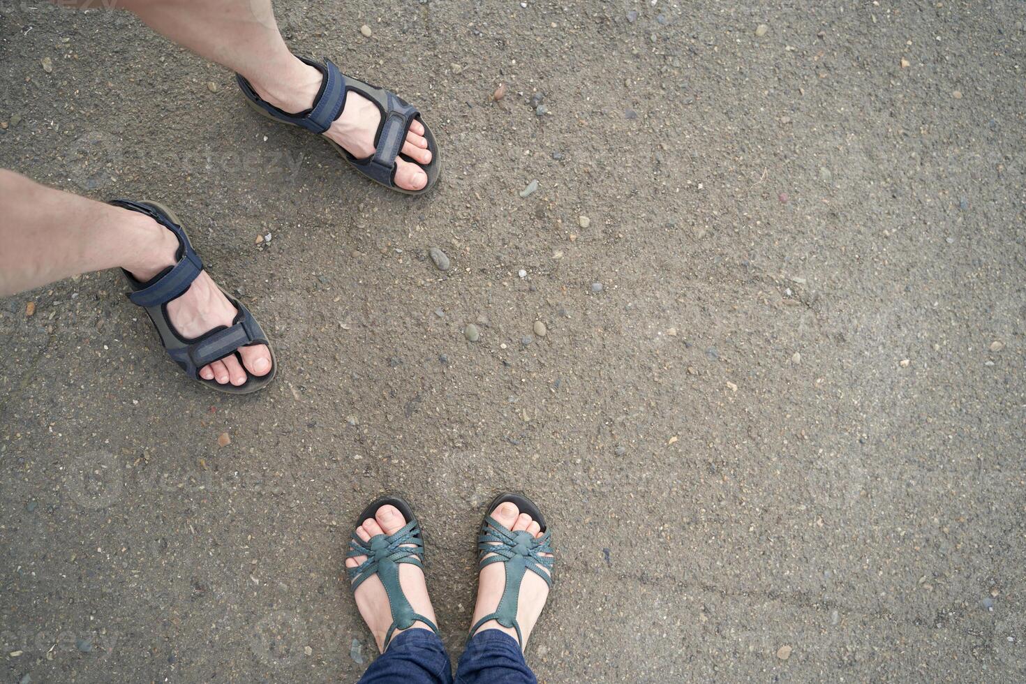 Sandaled feet on gravel road. Comfortable summer footwear outdoors view. photo