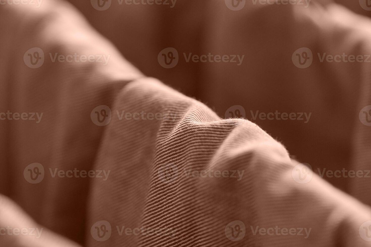 Close up view of wavy brown corduroy fabric texture in soft focus with warm lighting. photo