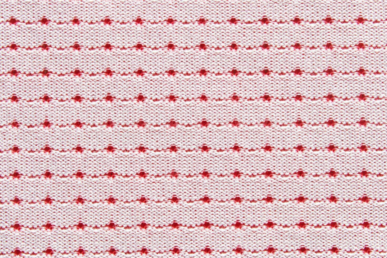 Red and white dotted pattern on knitted fabric background with repeating horizontal lines. photo