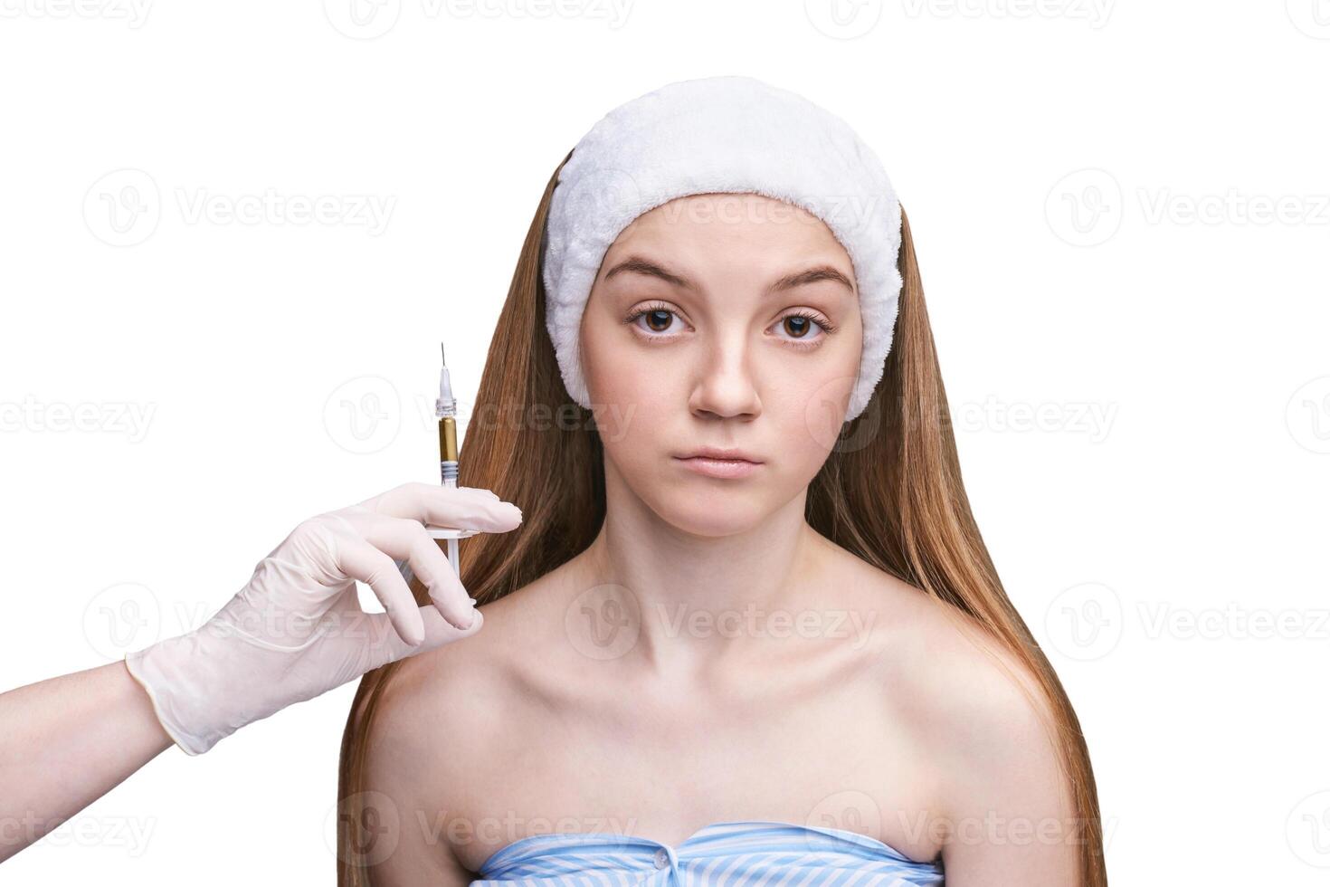 Young caucasian female receiving cosmetic injection by professional in gloves. photo