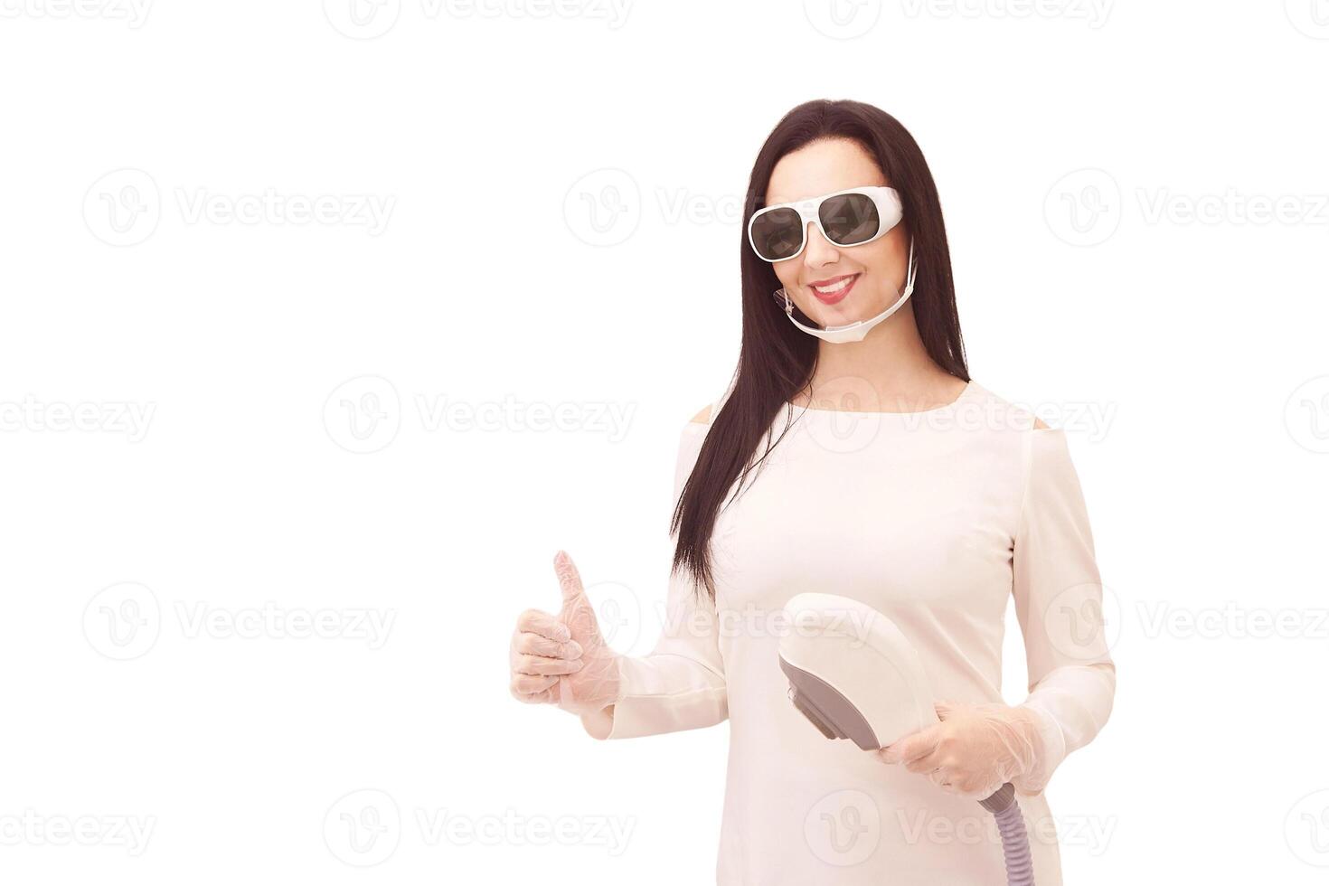 Young caucasian female smiling in protective glasses holding laser hair removal device. photo