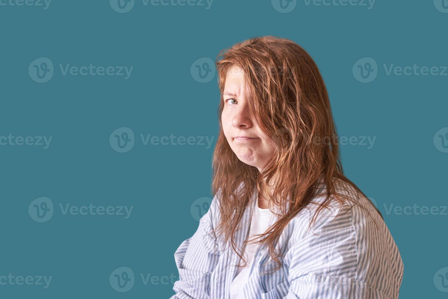 Young caucasian female with long brown hair in blue striped shirt facing sideways. photo