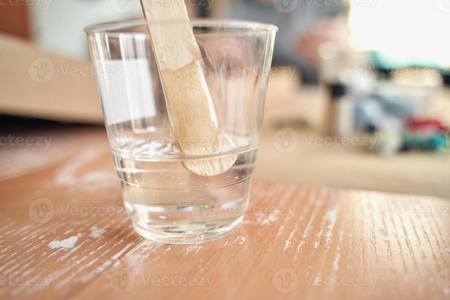 Clear plastic cup with stir stick on wooden surface in well lit room. photo