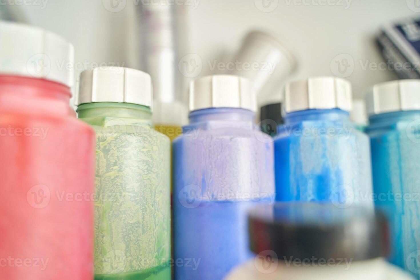 Colorful array of plastic paint bottles in a row on shelf closeup with focus on shapes and textures. photo